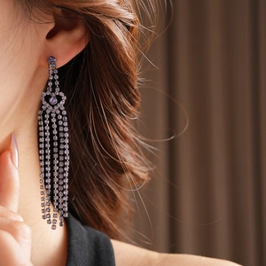 Gros plan de boucles d'oreilles franges argentées avec strass violets sur un mannequin