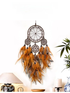 Detail of five-ring dream catcher with orange feathers and wood beads on wall