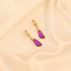 Détails de boucles d'oreilles dorées avec pendentifs en cristal sur fond en soie