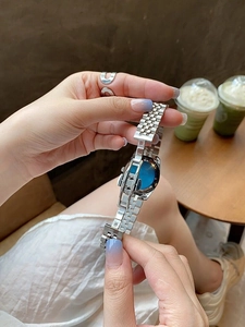 Detail of elegant silver metal watch band and blue dial worn on a woman's wrist