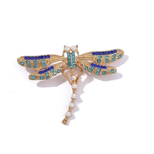 Detail view of dragonfly brooch with blue crystals and white pearls on gold plating