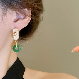 Detail of elegant gold-plated water drop earrings with green jade-like ring on a model