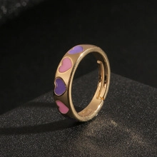 Detail of gold open ring featuring purple and pink enamel hearts in 45-degree close-up