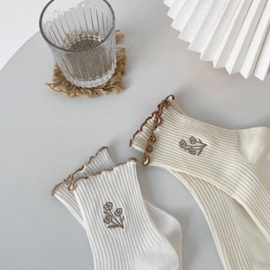 Japanese style cotton mid-calf socks with ruffle trim and floral embroidery on a table