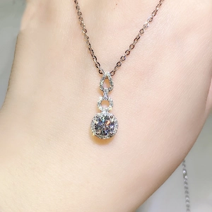Macro detail of a 2ct moissanite pendant necklace on neck showing brilliant fire and luster