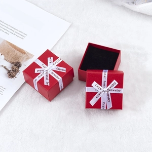 Macro shot of red jewelry boxes with printed white ribbons on a white plush surface