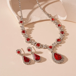 Luxurious vintage jewelry set with red teardrop gems and crystals on a stone background