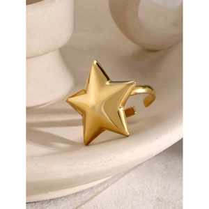 Polished gold star shaped open ring with a mirror finish on cream ceramic surface