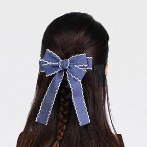 Denim ribbon bow hair clip with scalloped embroidery and long streamers on model