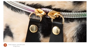 Detailed close-up of smooth gold dual metal zippers on a leopard faux fur cosmetic bag