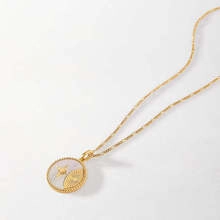 Detailed macro of gold snake chain necklace with mother of pearl bee coin pendant