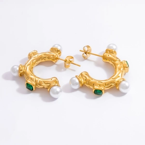 Detail view of 18k gold plated pearl earrings featuring a vintage green gemstone accent