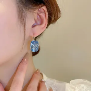 Elegant gold earrings with a rectangular blue crystal gem in a French Hepburn style design
