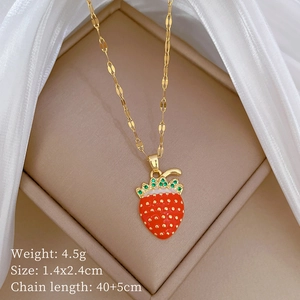 Macro shot of sparkling strawberry pendant necklace with red enamel and green crystals