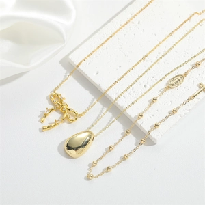 Detail of 14K gold plated necklace with zircon bow and polished teardrop pendants