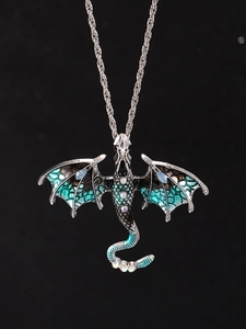 Macro detail of winged dragon pendant with green scales and sparkling crystals on chain