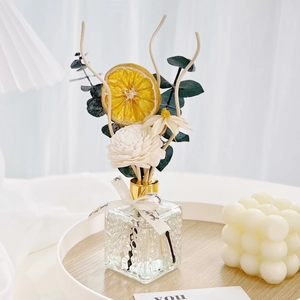 Detail of square glass reed diffuser with dried orange, flowers and eucalyptus