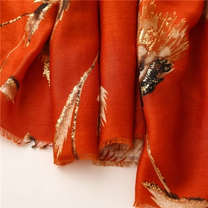Macro detail of red and orange cotton-linen scarf with elegant golden foil patterns
