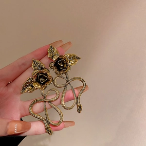 Detailed view of vintage gold snake and rose earrings with intricate metal texture