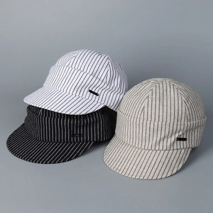 Detailed macro view of pinstripe newsboy caps in black, white, and grey with side logo metal tags