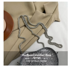 Detail of silver sequin mini heart bag with elegant metal chain strap on beige blazer