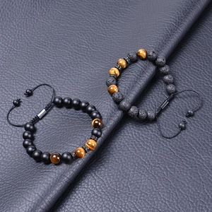 Detail of 10mm tiger eye and lava stone beads with adjustable braided cord on leather background