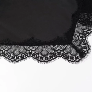 Détail macro de la dentelle noire et des bords cils sur le tissu d'une robe en satin