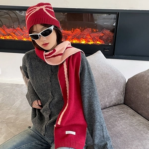 Winter red knitted bow pattern hat and scarf set shown in a cozy fireplace setting