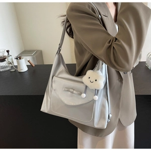 Detail of silver tote bag featuring a cute bow pocket and white cloud plush pendant charm