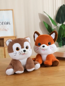 Close-up of soft plush cat and fox dolls sitting on a wooden table in a warm cozy setting