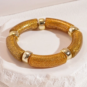 Close-up of golden glitter resin bracelet with polished metallic bead spacers on stone