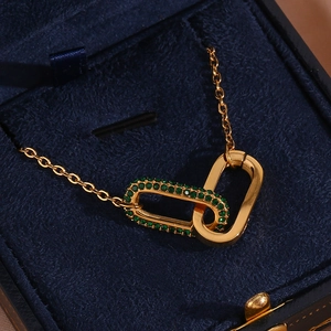 Gold stainless steel necklace with interlocking rings and green crystal pendant in a box