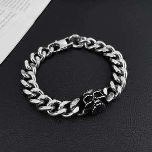 Detail of silver skull charm on a stainless steel Cuban link bracelet for men