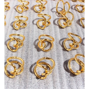 Golden chunky knotted open rings in a grid layout on textured grey background