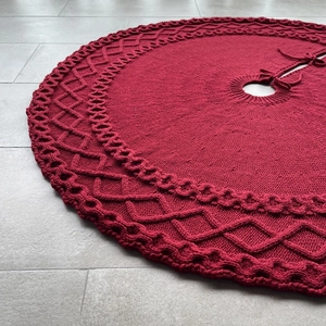 Détail de la jupe de sapin de Noël rouge en tricot avec texture torsadée et attaches
