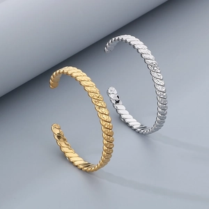 Detailed view of gold and silver twisted texture metal open bangles with mirror finish
