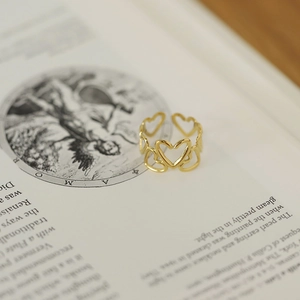 Gros plan d'une bague large dorée avec motif de cœur sur des pages de livre vintage Amor