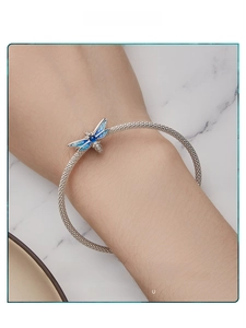 Detail view of a silver mesh bracelet featuring a blue enamel dragonfly charm with zircons