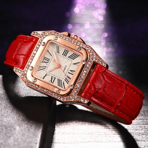 Macro view of rose gold square watch case with sparkling crystals and red leather strap