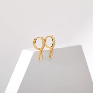 Detailed close-up of gold geometric drop earrings featuring sparkling zircon stone settings