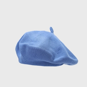 Detailed view of the fine knit texture and small tip on a light blue cotton beret hat