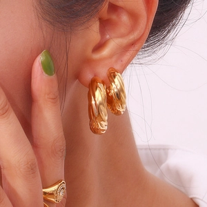 Close-up of a model wearing gold hollow C-shape twisted hoop earrings in 18K plating
