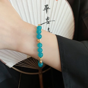 Close-up of vintage beaded bracelet with blue stones and golden pixiu charms on wrist