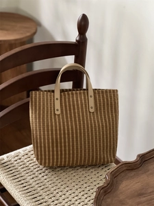 Macro shot of brown striped tote bag with leather handle and rivets on a chair