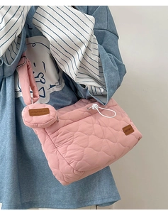 Détail d'un sac bandoulière rose matelassé avec pochette ronde et cordon de serrage