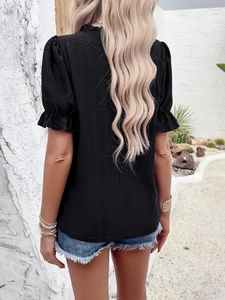 Detail of black textured t-shirt featuring ruffle sleeves and elegant lace cutouts