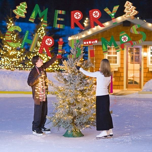 Outdoor festive scene with people hanging a red and green Merry Christmas banner
