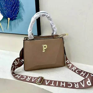 Close-up of brown leather tote with golden logo and woven PARCHITA shoulder strap