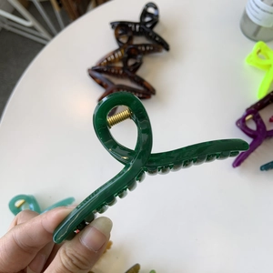 Detailed view of the translucent dark green acrylic hair claw clip held by hand