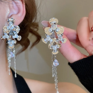 Detail of sparkling floral tassel earrings featuring silver metal and crystal water drops